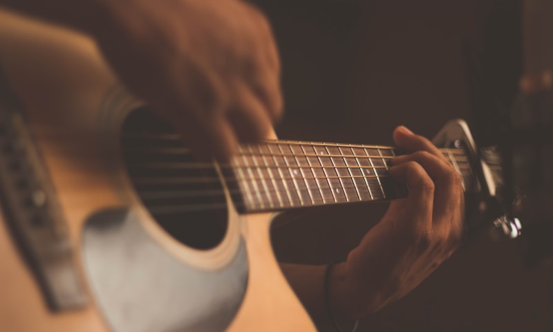 Persona aprendiendo a tocar la guitarra acústica